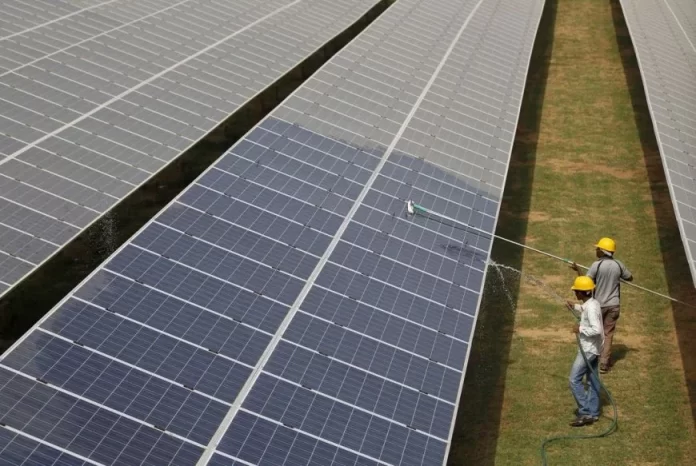 Workers clean photovoltaic panels inside a solar power plant in Gujarat, India, July 2, 2015.