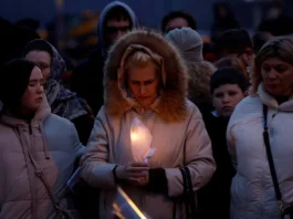 A woman holds a candle in front of a makeshift memorial to the victims of a shooting attack set up outside the Crocus City Hall concert venue in the Moscow Region, Russia. REUTERS/Maxim Shemetov